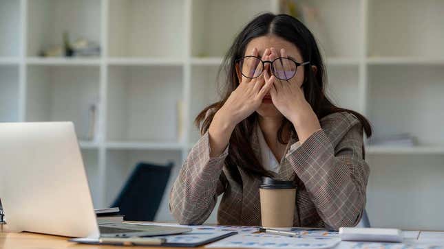 A photo shows a frustrated woman sitting behind her desk.